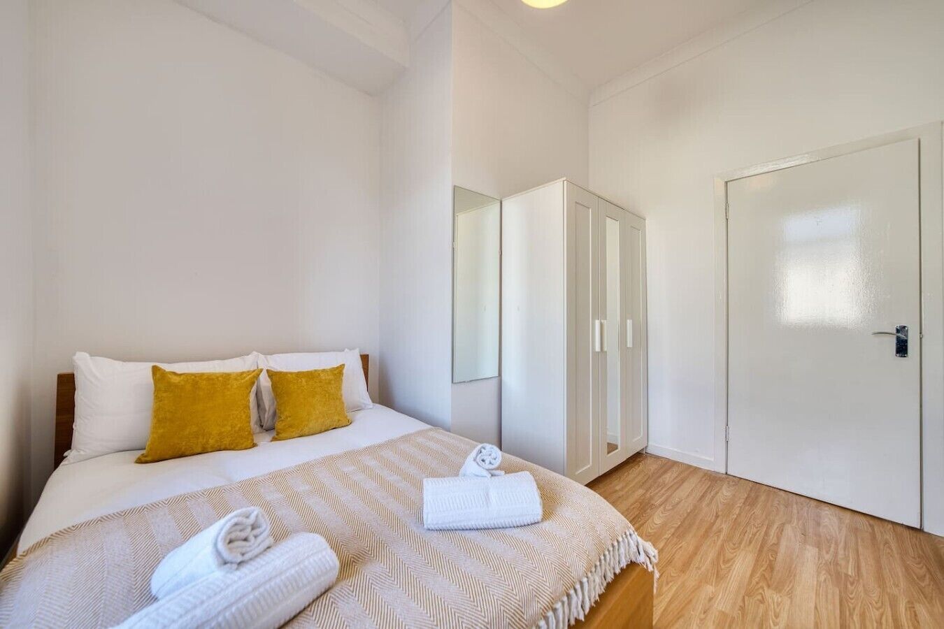 A bedroom with a bed, a wardrobe, and a door.