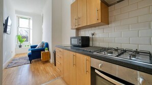 Een moderne keuken met houten kastjes, een gasfornuis en een magnetron.