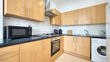 Eine moderne Küche mit Holzausstattung, einer Mikrowelle, einem Herd, einem Backofen und einer Waschmaschine.
