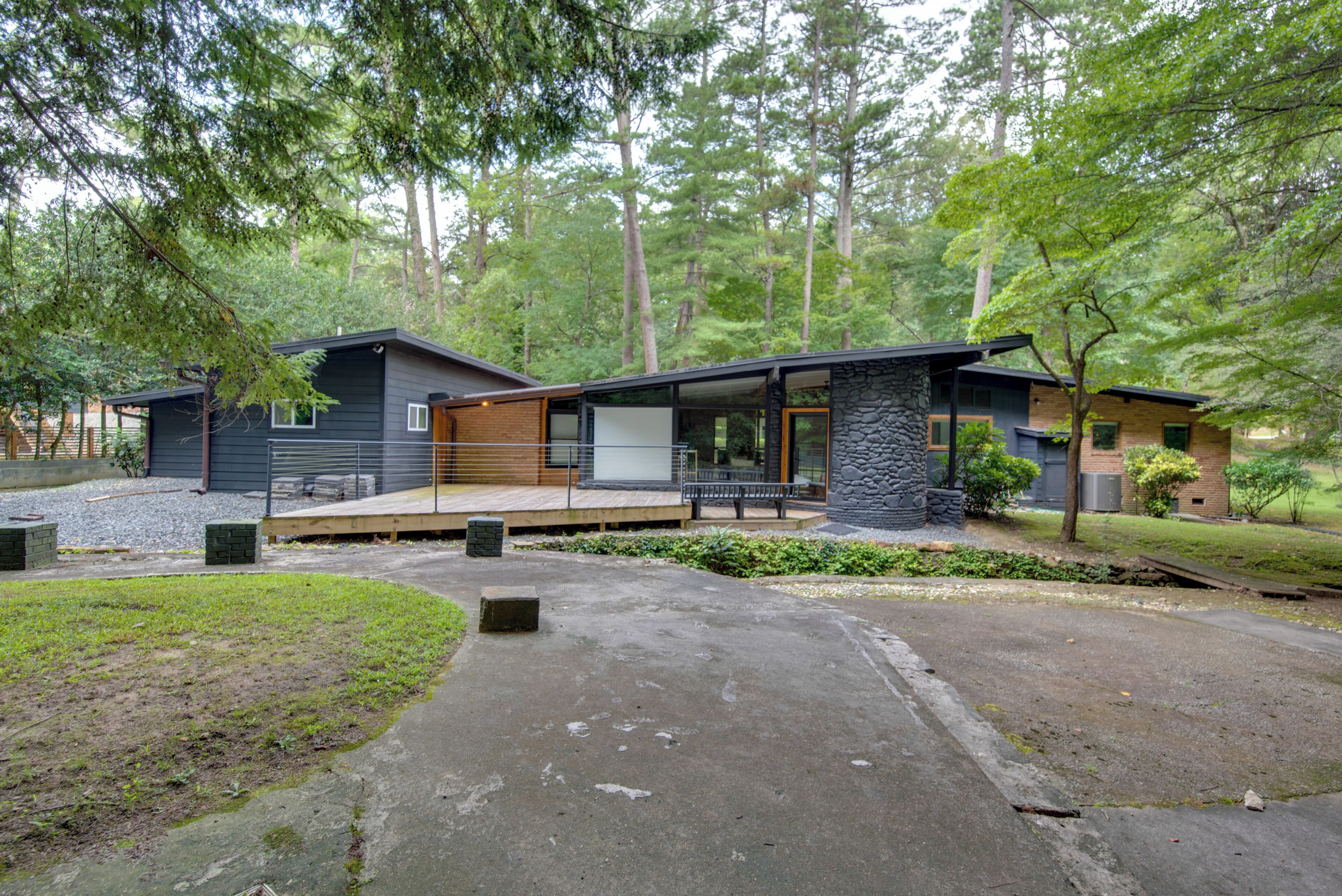 A modern two-story house with a stone exterior, a wooden deck, and a stone pillar.
