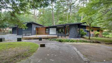 A modern two-story house with a stone exterior, a wooden deck, and a stone pillar.