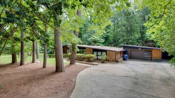 A modern house with a garage, surrounded by trees and a well-maintained lawn.