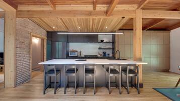 A modern kitchen with a central island, bar stools, and built-in appliances.