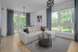 A modern living room with a grey sofa, a glass coffee table, and a vase of flowers. - Lumina modern Apart parking 2 balcony (Warszawa)