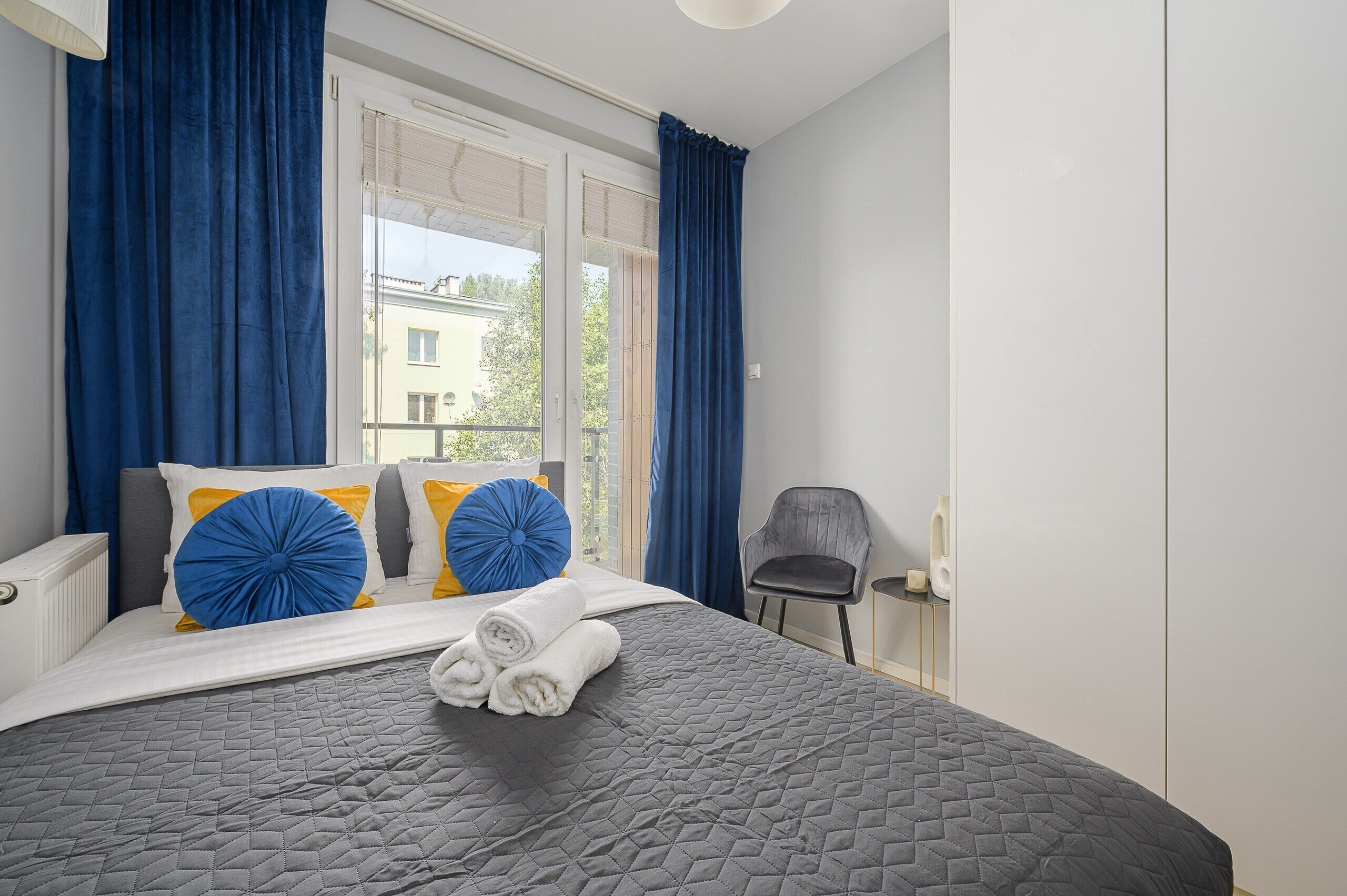 Quarto com cama, uma cadeira e vista para o exterior.