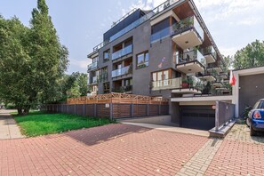 A multi-story residential building with balconies, a gated entrance, and a paved driveway. - Lumina modern Apart parking 2 balcony (Warszawa)