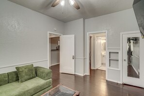 A living room with a green sofa, wooden flooring, and a ceiling fan. - Walk Everywhere! Monte Vista Apartment Near Cafes (San Antonio)