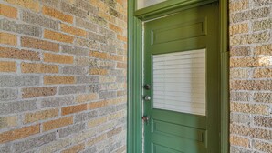 Una porta verde con una finestra e una serratura, incastonata in un muro di mattoni.
