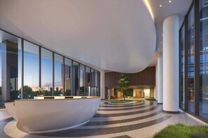 A modern lobby with a reception desk, large windows, and a circular seating area.