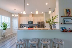 A modern kitchen with white cabinets, stainless steel appliances, and a central island with bar stools. - Near Tyndall AFB & the Beach! Panama City Retreat (Panama City)