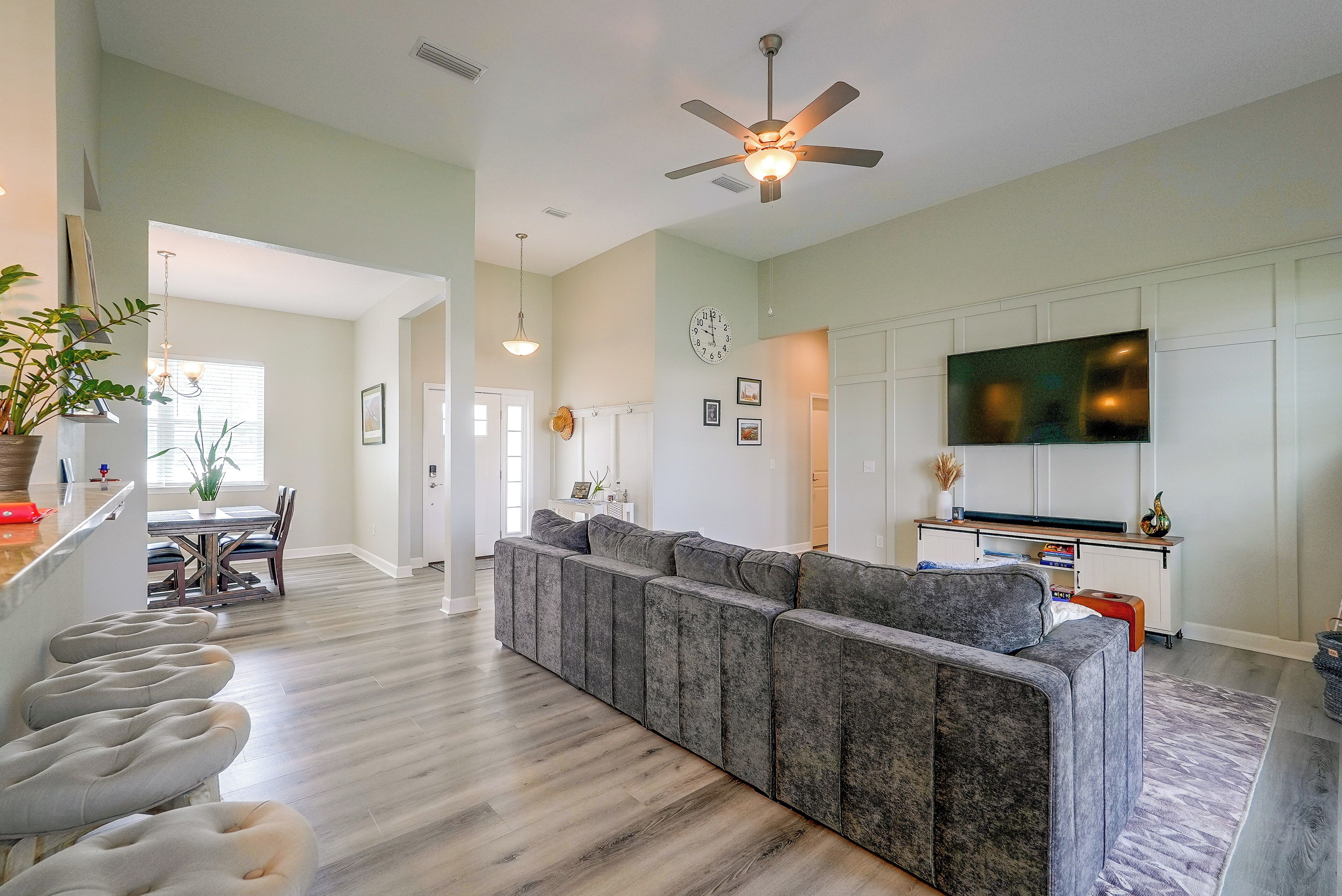 A spacious living area with a sectional sofa, a dining table, and a flat-screen TV mounted on the wall.