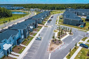 A residential area with modern apartment buildings, a main road, and a small lake. - Special Offer! Cozy Townhome/Private Pool/Themed BRs 3011PL (Kissimmee)