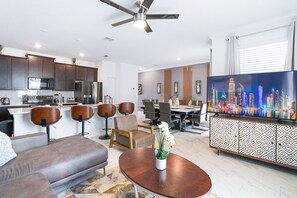 A modern living room with a sofa, a coffee table, and a TV displaying a cityscape. - Special Offer! Cozy Townhome/Private Pool/Themed BRs 3011PL (Kissimmee)