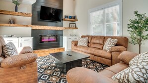 A modern living room with a fireplace, leather sofas, a coffee table, and a TV mounted on the wall. - Helen Family Home w/ Innsbruck Resort Perks! (Helen)
