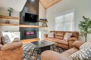 Ein modernes Wohnzimmer mit Kamin, Ledersofas, einem Couchtisch und einem an der Wand befestigten Fernseher.