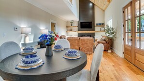 A modern dining area with a round table set for four, a sofa, and a TV mounted on the wall. - Helen Family Home w/ Innsbruck Resort Perks! (Helen)