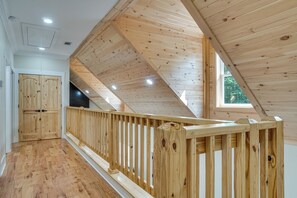 Ein Holzinnenraum mit schrägverdeckter Decke, einer Holzreling und einer Tür.