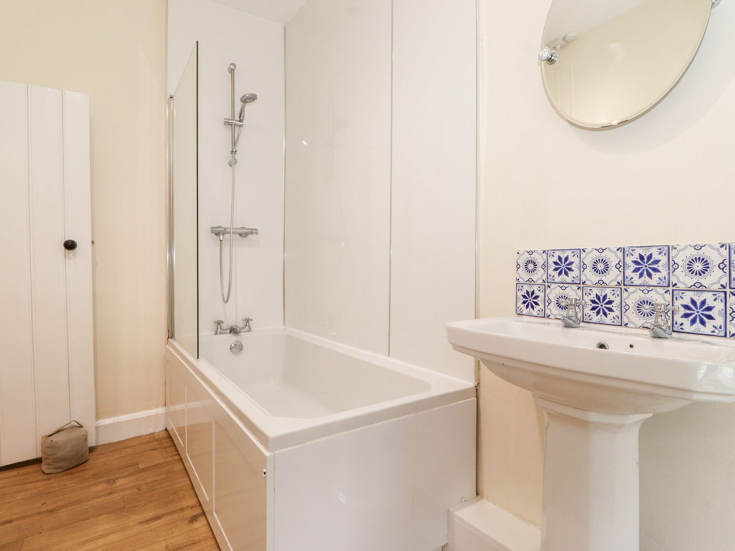 Un baño con bañera, ducha y lavamanos con detalles de azulejos decorativos.