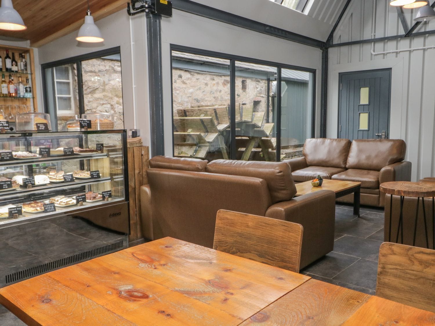A cozy cafe interior with leather seating, a display case of pastries, and a view of the outside.