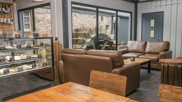 A cozy cafe interior with leather seating, a display case of pastries, and a view of the outside.
