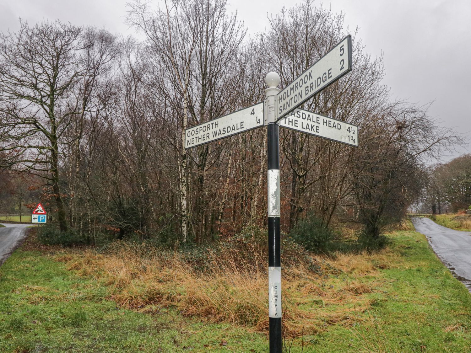 A directional signpost with multiple arms pointing towards destinations such as Gosforth, Nether Walsdale, Holmrook, and others.