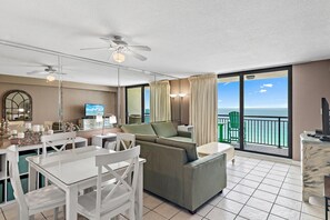 A hotel room with a balcony, a dining area, and a seating area with a view of the ocean. - Sundestin 1409 (Destin)