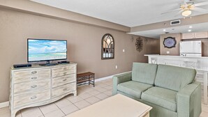 A living room with a television, a sofa, a small table, a decorative mirror, and a ceiling fan. - Sundestin 1409 (Destin)