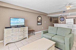 A living room with a television, a sofa, a small table, a decorative mirror, and a ceiling fan. - Sundestin 1409 (Destin)