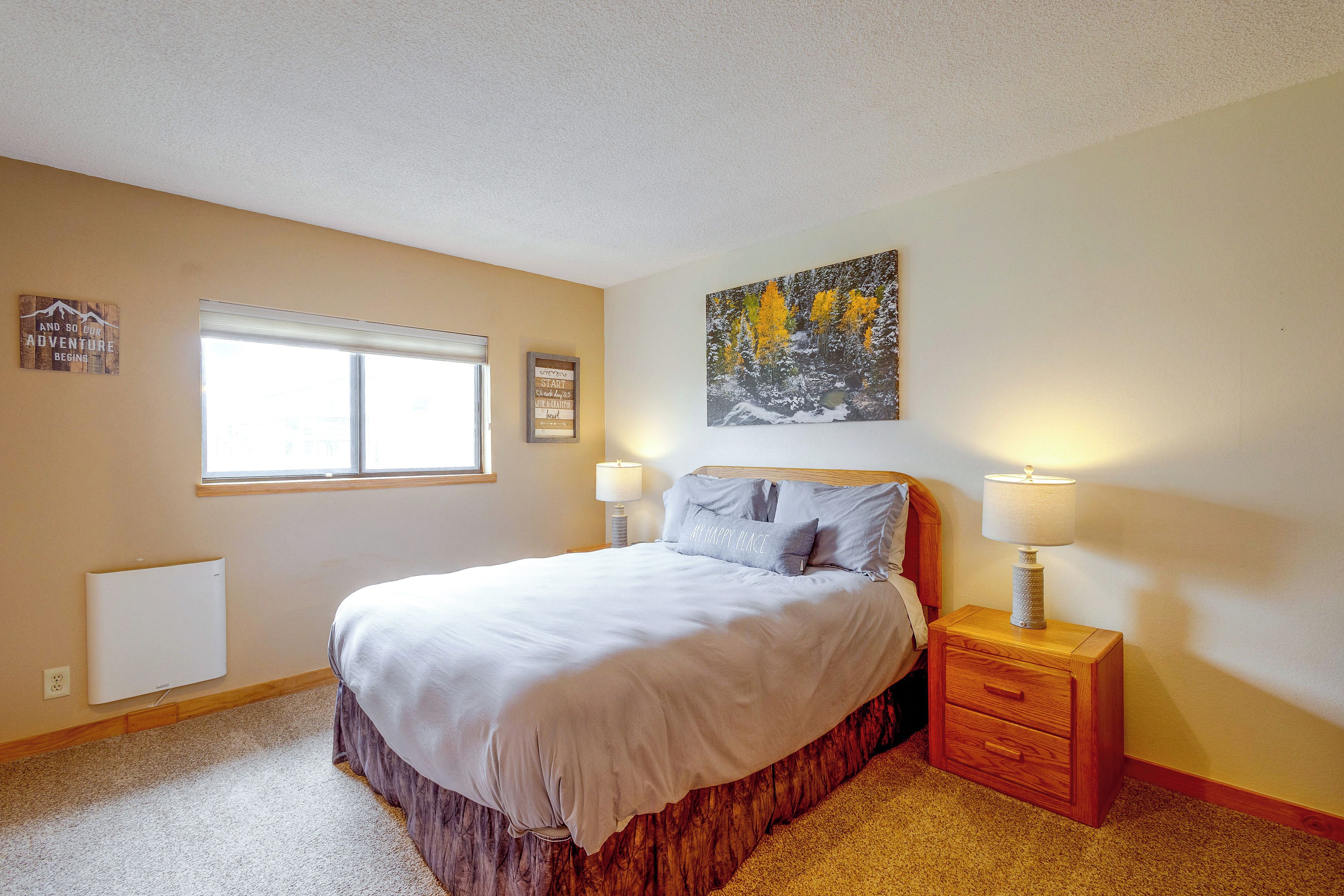 A bedroom with a bed, bedside lamps, a window, and wall decorations.