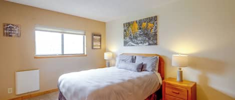 A bedroom with a bed, bedside lamps, a window, and wall decorations.