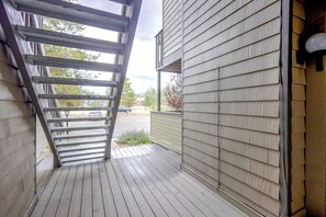 Una terraza de madera con una escalera metálica que lleva a un espacio cubierto.
