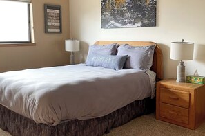 Un dormitorio con una cama, dos lámparas de noche, una mesita de noche, una cita enmarcadas en la pared y un cuadro sobre la cama.
