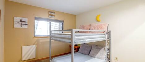 Una cama litera con un adorno de luna, una ventana y una obra de arte en la pared.