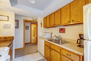 Una cocina con armarios de madera, microondas, cafetera y un cartel que dice 'Ski'.