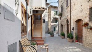 A narrow street with a bench and a table, flanked by buildings with stone facades and wooden shutters. - Apartment Di Luce near Assisi' with Wi-Fi (Petrignano)