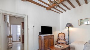 A living room with a television on a wooden cabinet, a chair, a floor lamp, and a sofa. - Apartment Di Luce near Assisi' with Wi-Fi (Petrignano)