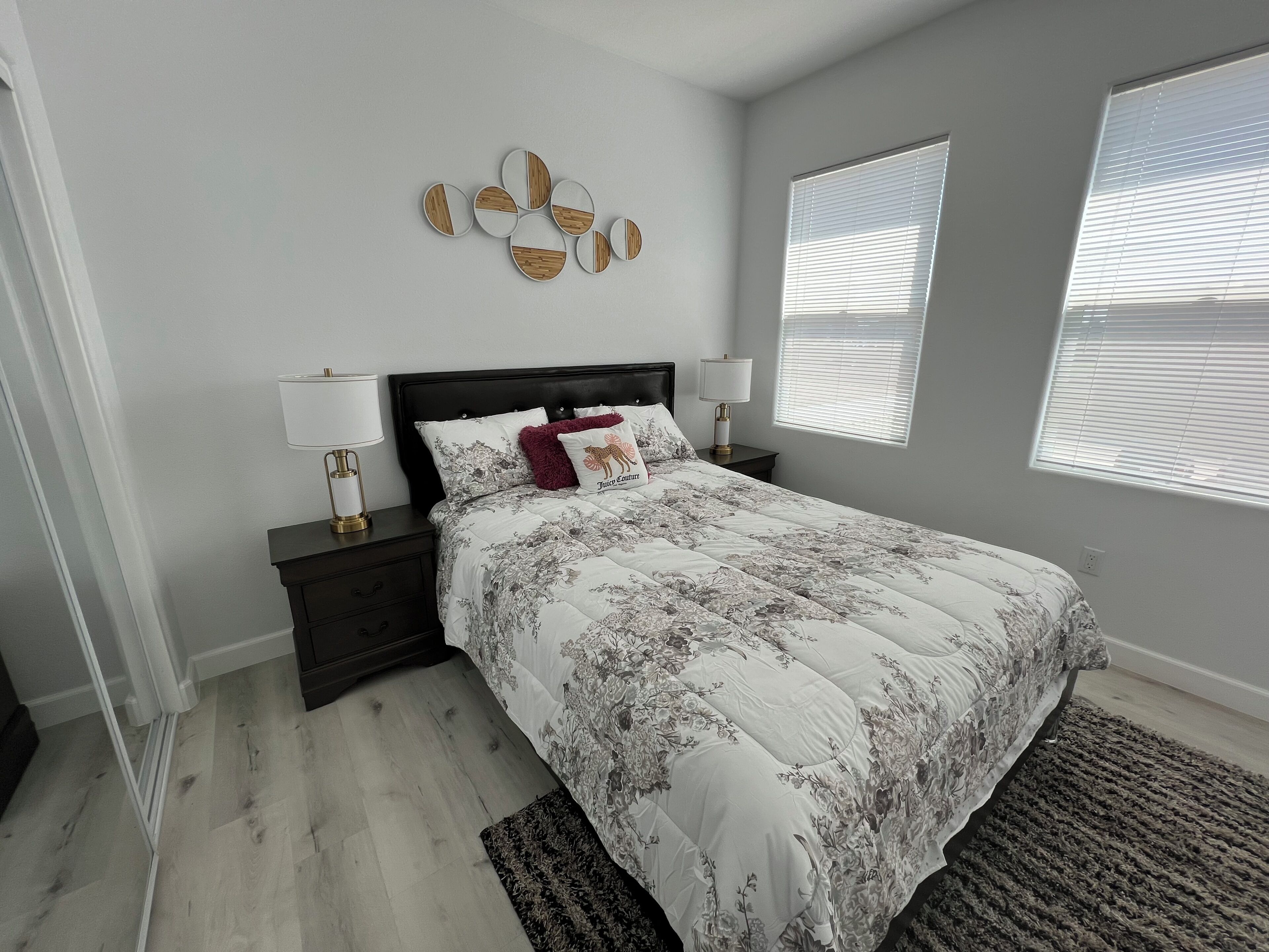 A bedroom with a bed, nightstands, a wall clock, and a window.