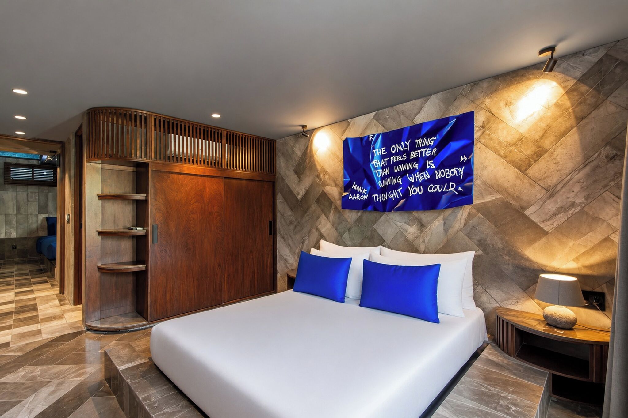 A modern bedroom with a large bed, a wardrobe, and a motivational quote on the wall.