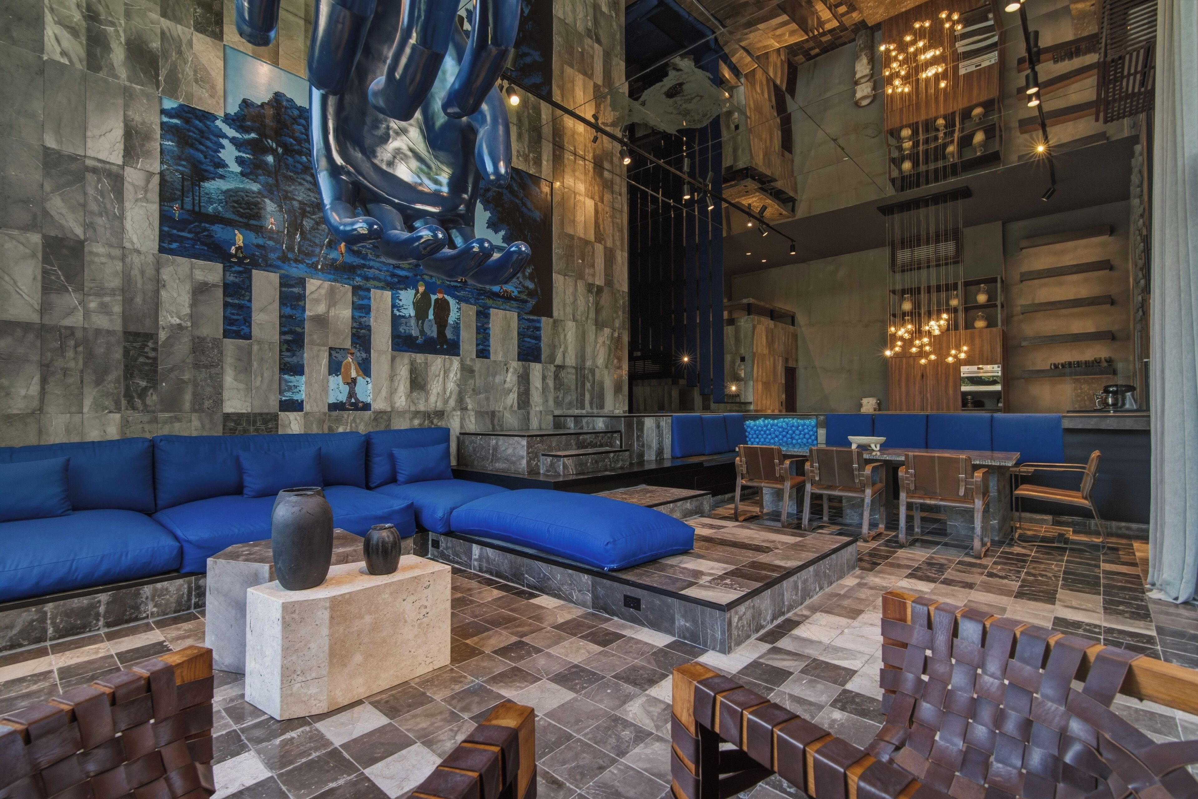 A modern interior with a blue sofa, wooden chairs, and a large abstract painting on the wall.