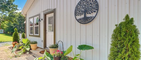 Un bâtiment orné d’une décoration métallique en forme d’arbre, avec une porte, des fenêtres et des plantes en pot.