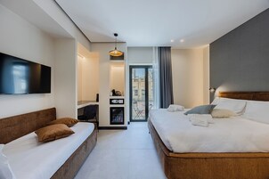 Une chambre d’hôtel moderne équipée d’un lit, d’un canapé, d’un bureau, d’une télévision à écran plat et d’un mini-bar.