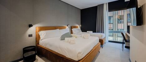 Una habitación de hotel moderna con una cama grande, mesitas de noche, una silla y un televisor montado en la pared.
