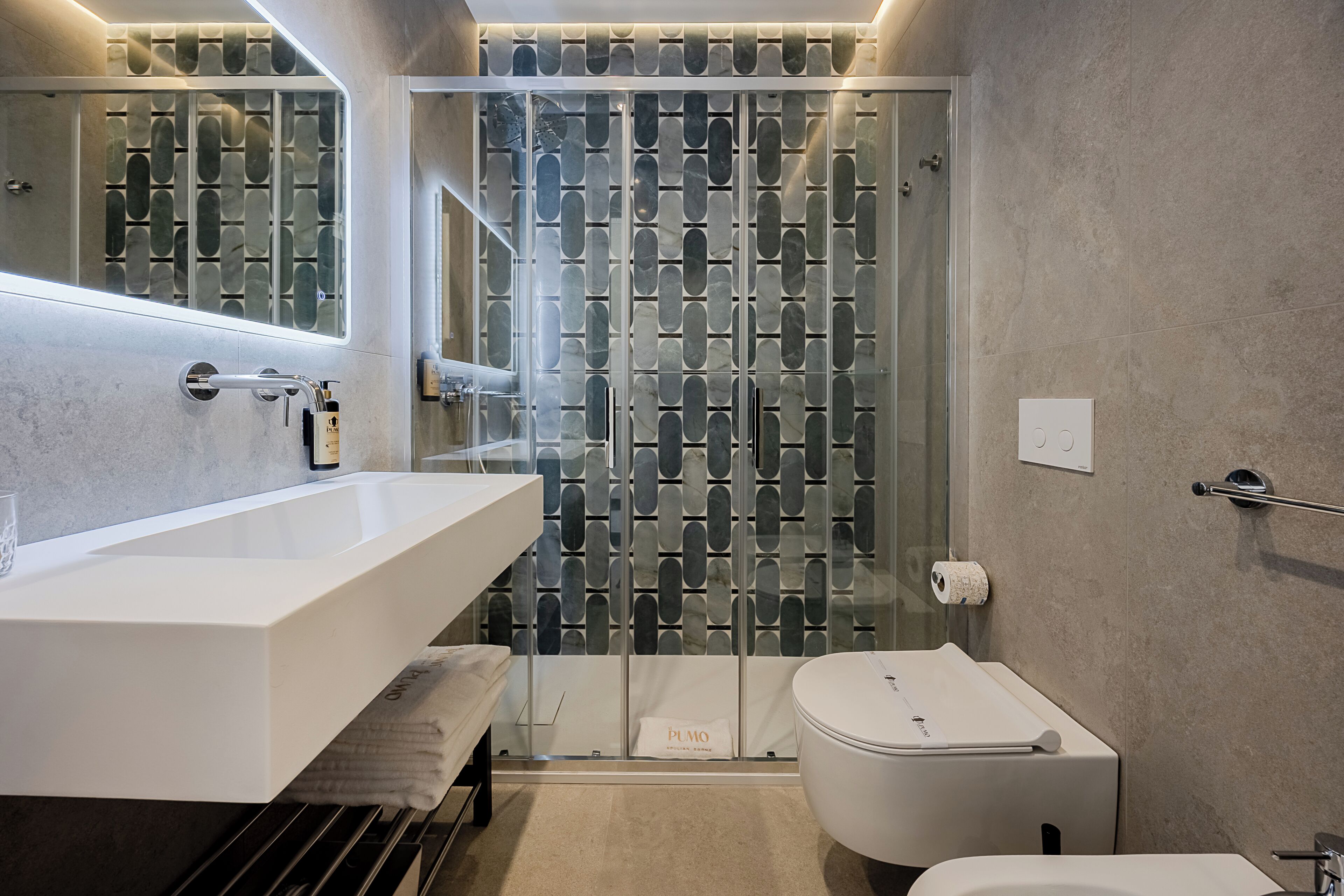 Et moderne badeværelse med en glas brusekabine, en hvid vask og et toilet.
