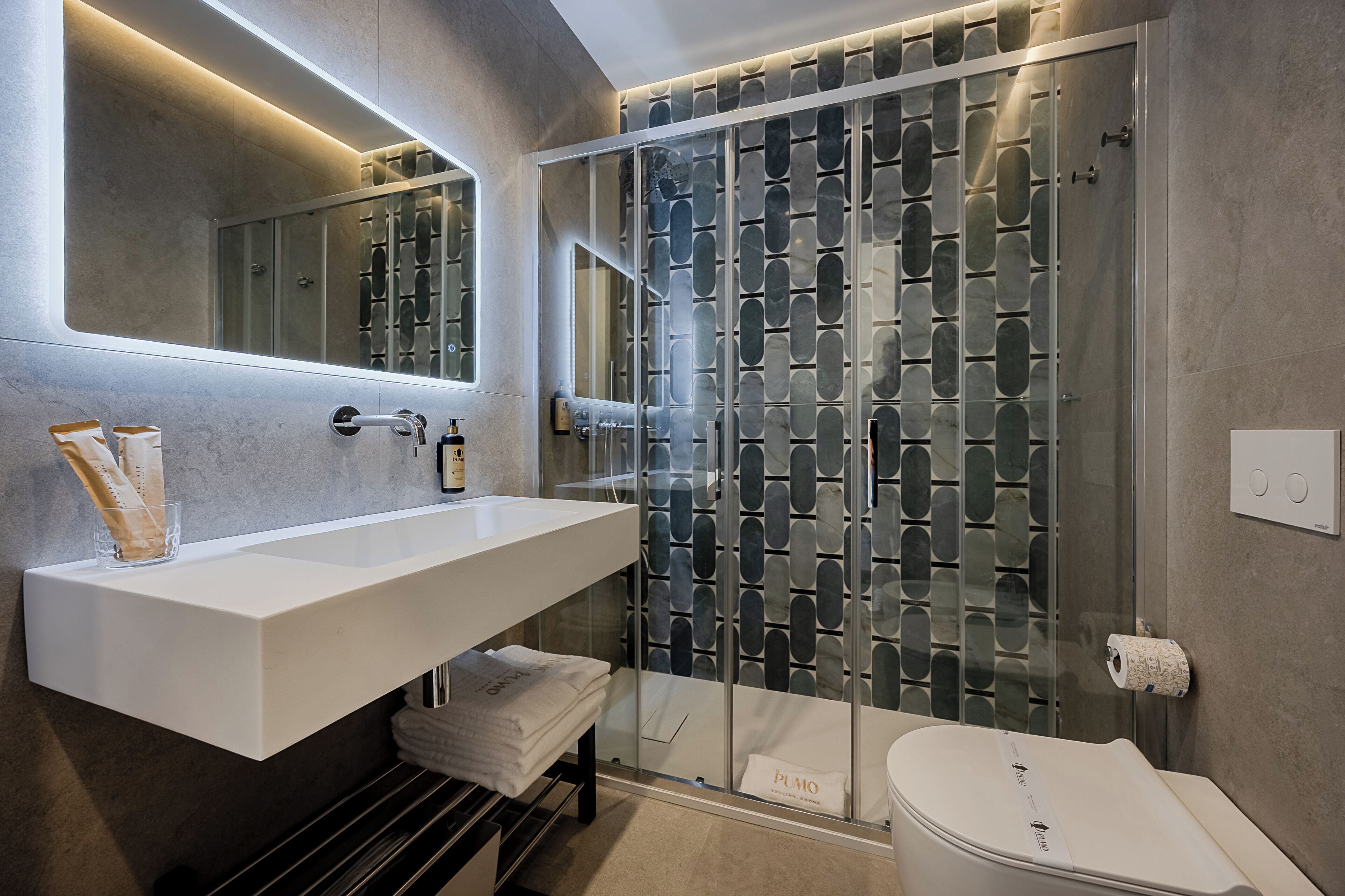 Ein modernes Badezimmer mit einer Duschkabine aus Glas, einem weißen Waschbecken und einer Toilette.
