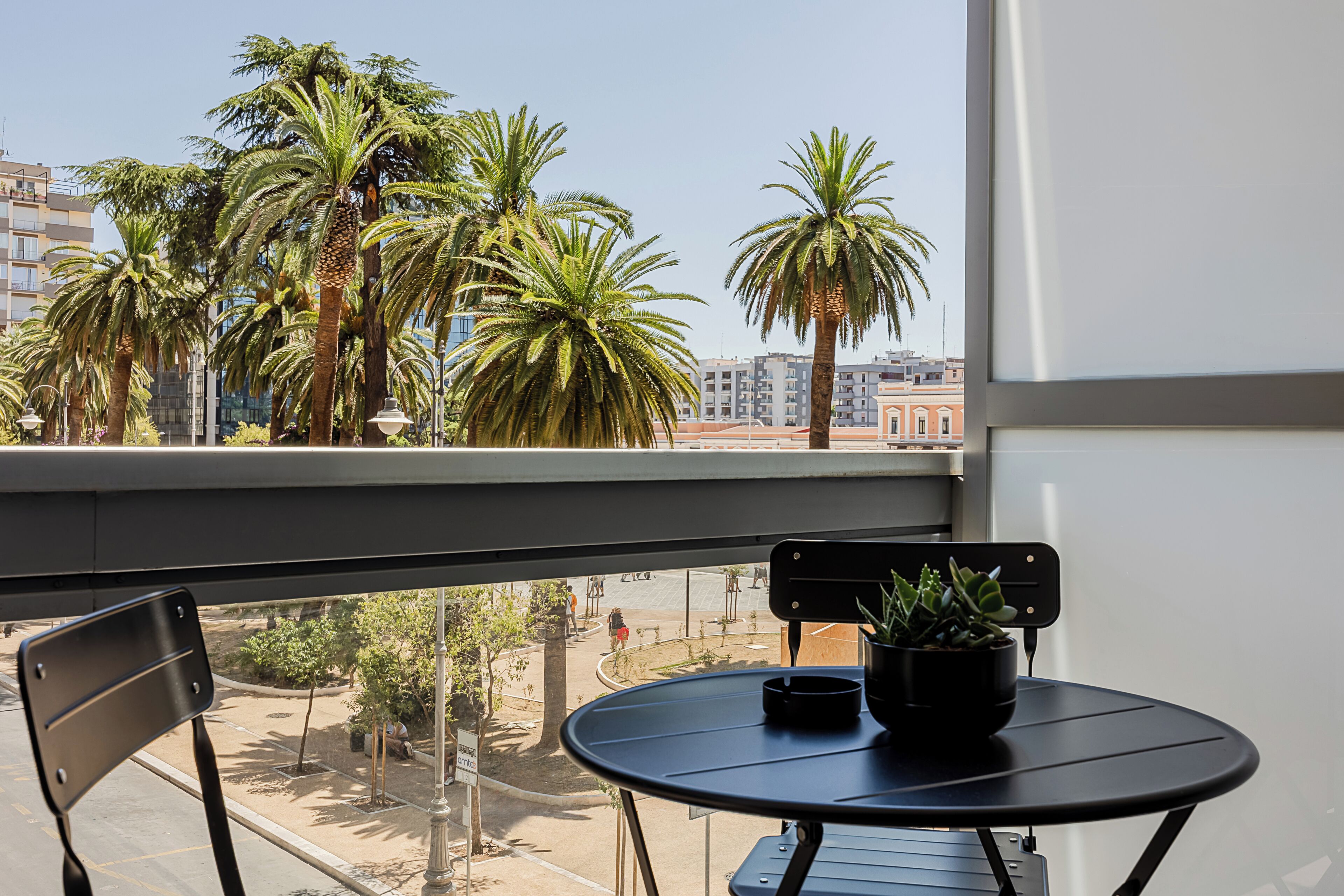 Un balcone con tavolo, sedie e piante in vaso.