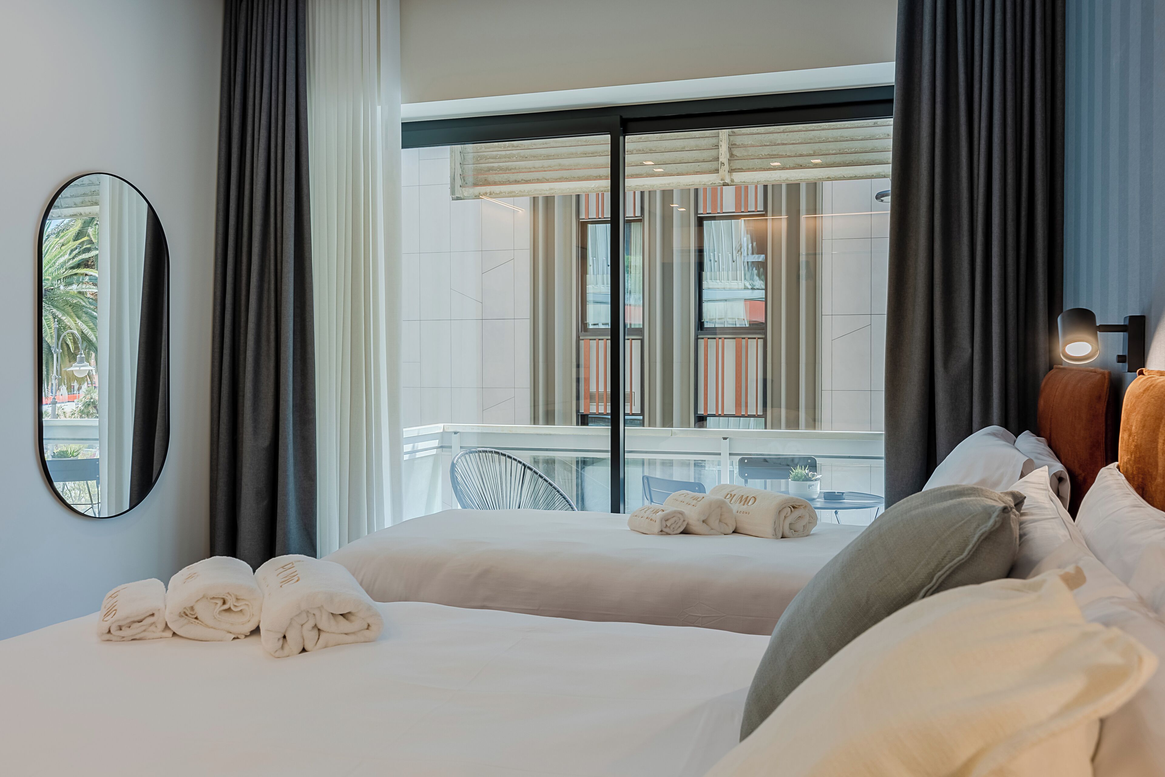 A hotel room with two beds, a balcony, and a view of the outside.