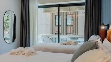 A hotel room with two beds, a balcony, and a view of the outside.