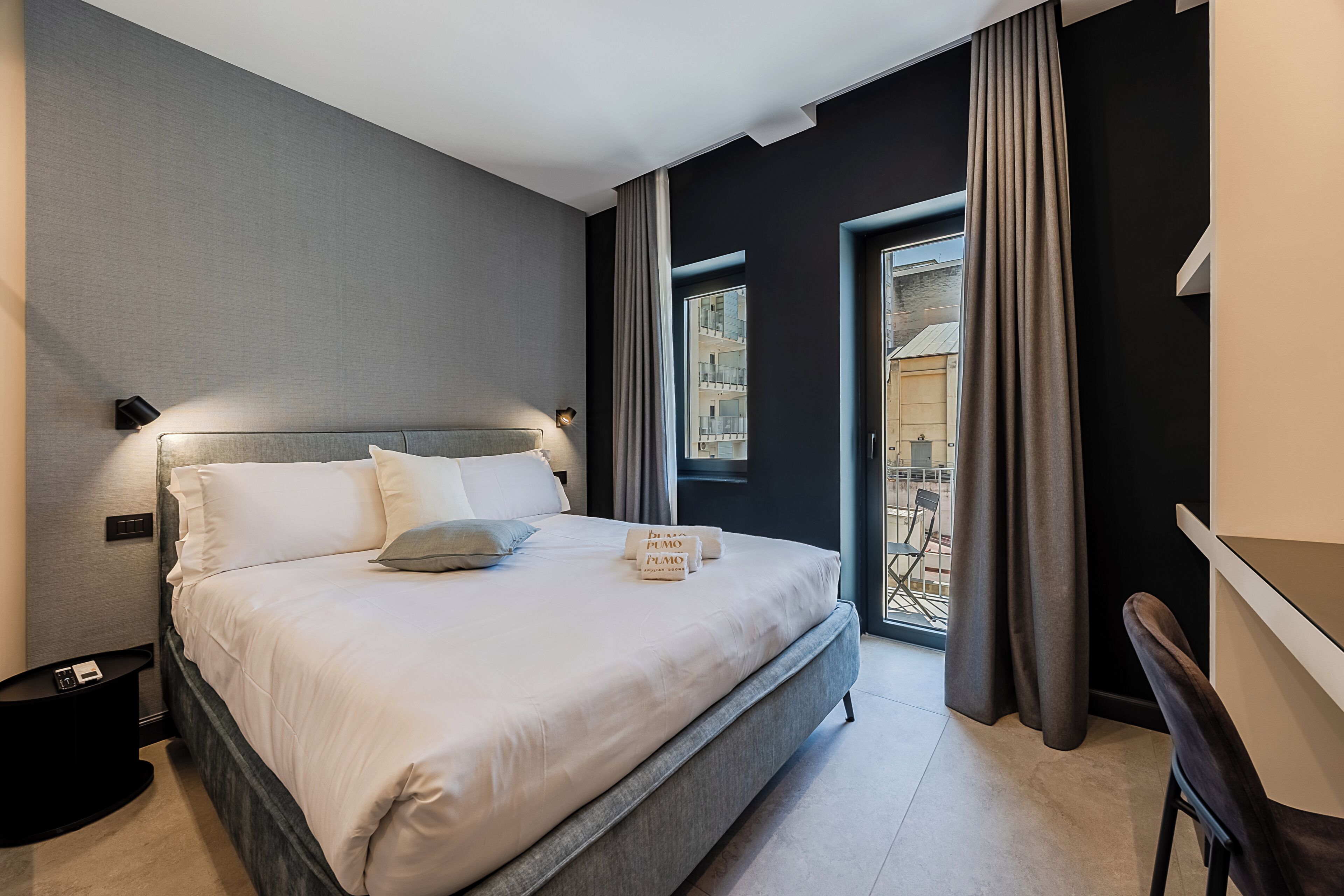 Quarto de hotel moderno com uma cama grande, uma escrivaninha e vista para o exterior.