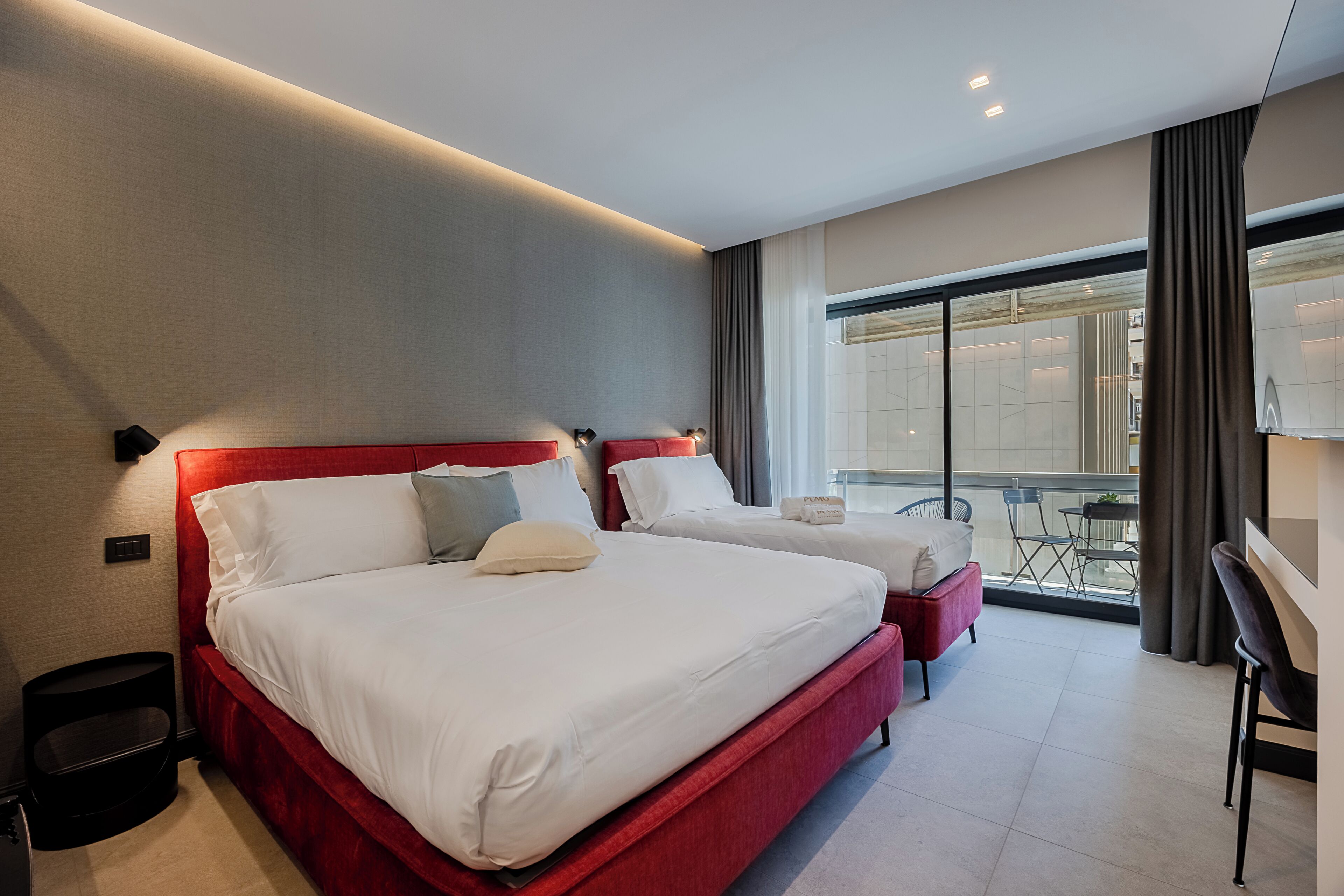 Une chambre d’hôtel avec deux lits, un balcon et un bureau.
