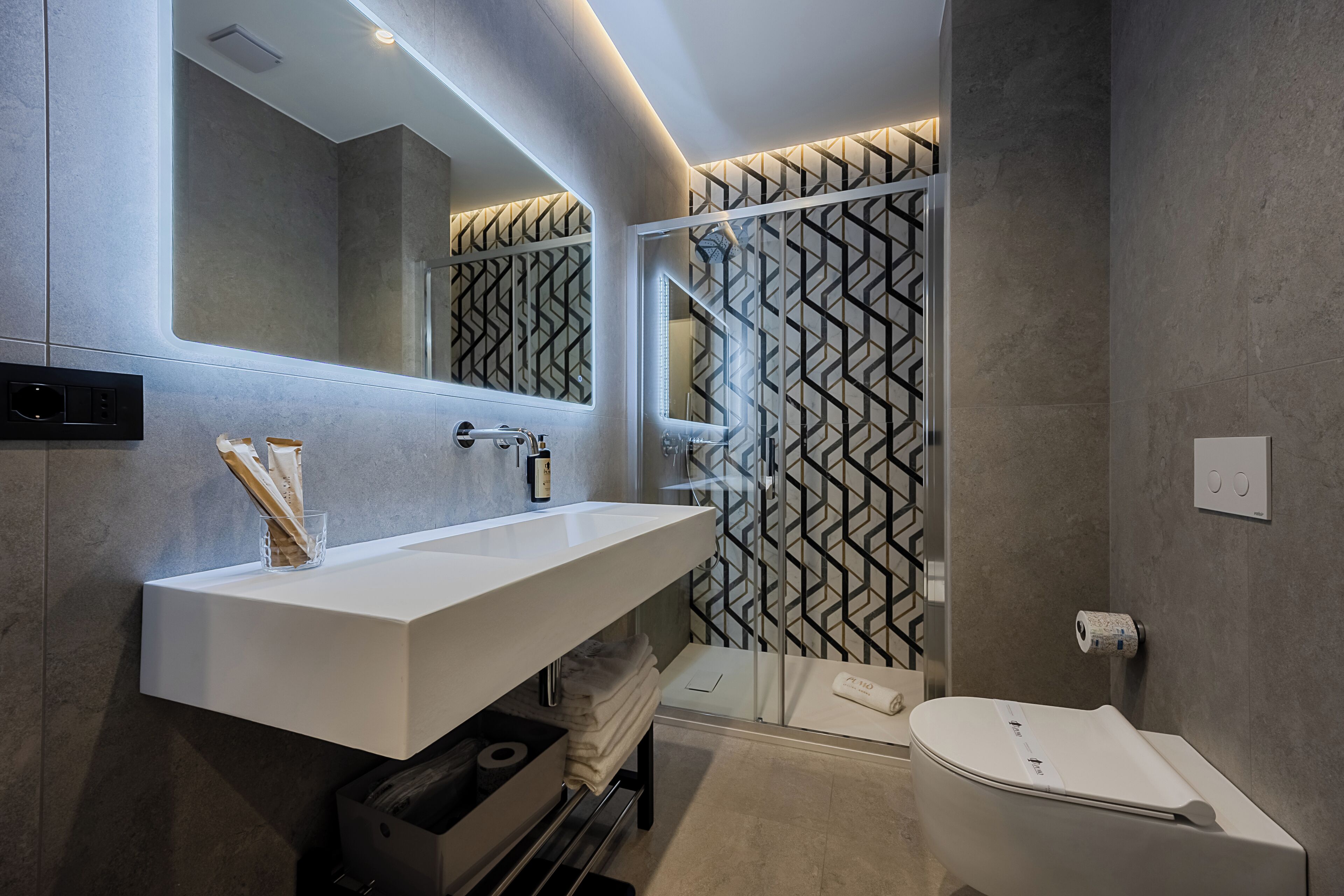Ein modernes Badezimmer mit einem weißen Waschtisch, einer Glasdusche und einer Toilette.
